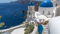 Oia Santorini Greece. Blue domes of Oia. Fashion model. Blue Dress. White Hat.